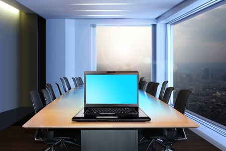 black laptop on a table in empty modern officeの写真素材