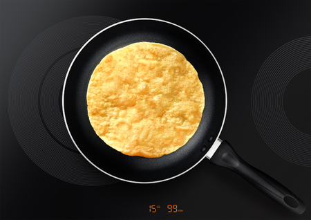 black frying pan with pancake on induction plateの写真素材