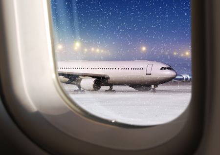 airport and white aircraft at non-flying weather, view through a plane windowの写真素材