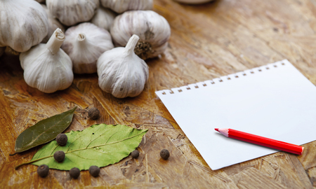 blank for recipe or note with pensil on wooden surface with garlic and spicesの写真素材