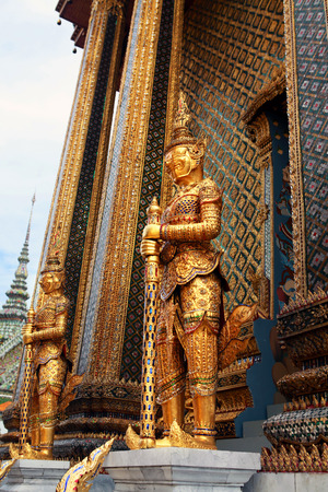 Statue of the golden guard at an entrance to the Phra Mondop templeの写真素材