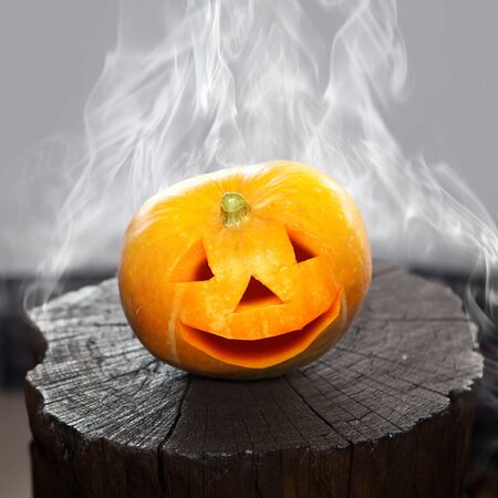 Pumpkin that laughs on a charred stub in smoke. Scenery for Halloween holiday.の写真素材