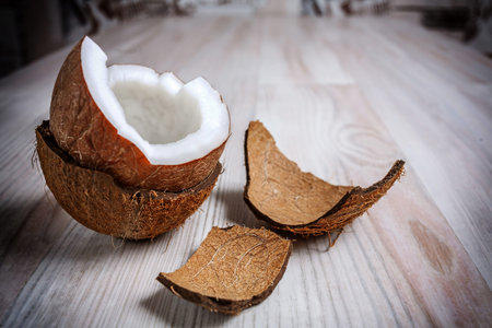 On the light surface of the table is one half the coconut in the hairy shell close up. Next to the...