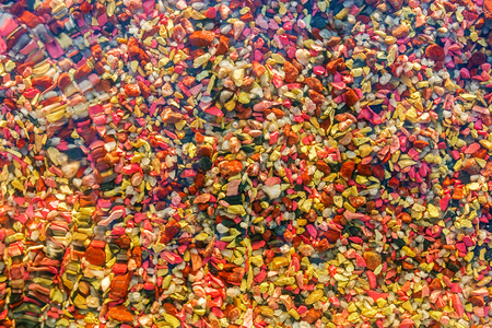 Texture of colored stones on the bottom under water. On the water a little waviness. It can be used as a background.の写真素材