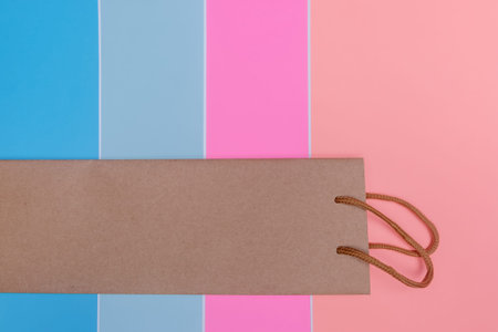 Craft paper shopping bag on colorful striped paper textured backdrop. Use copy space for sale and...