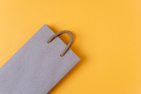 Craft paper shopping bag on yellow paper background. Store and sale concept.の写真素材