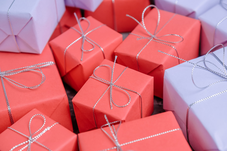 Mixed gifts wrapped in red and lilac paper and tied with silverの写真素材