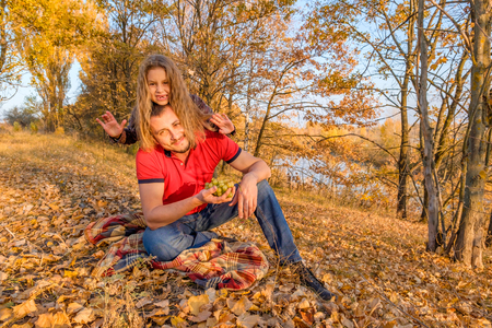 In the autumn park near the river. Concept of single father parenting and happy family.の写真素材