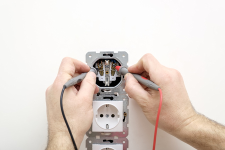 Electrician measuring voltage in the outlet using a multimeter in hands. Closeup view, copy spaceの写真素材