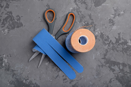 Colored kinesio tapes and scissors on concrete background. top viewの写真素材