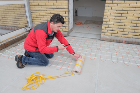 Electrician installing heating electrical cable on concrete floor. Man read instruction.の写真素材