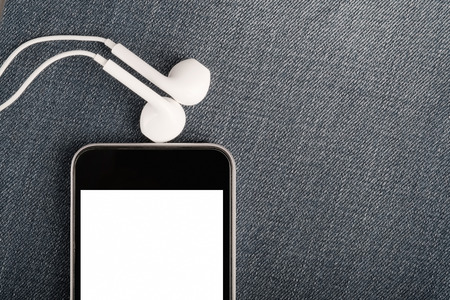 Mock up with modern smartphone and earphones on denim background. Copy spaceの写真素材