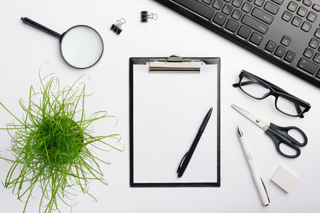 black clipboard mockup. Workspace with black keyboard, glasses, pens, eraser, scissors and other office accessories. Flat lay, copy space, top viewの写真素材