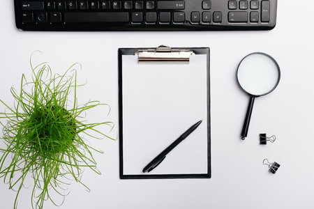 black clipboard mockup. Home office desk workspace with black keyboard, pen, magnifying glass, clips and office plant. Flat lay, copy space, top viewの写真素材