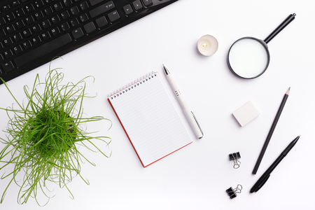 Home office desk with black keyboard, notebook, candle, pen, plant and other office accessories. Flat lay, copy space, top viewの写真素材