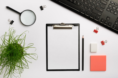 black clipboard mockup. Home office desk workspace with keyboard, sticker, eraser and other office accessories. Flat lay, copy space, top viewの写真素材