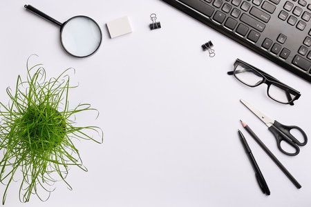 Office space works with black keyboard, glasses, pen, pencil, eraser, scissors, clips and office plant. Flat lay, copy space, top viewの写真素材
