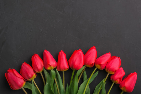 Bouquet of fresh red tulips on black background with copy space for text. Festive greeting card conceptの写真素材