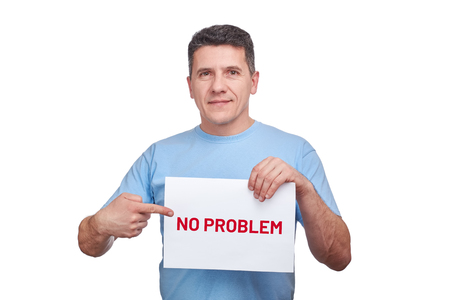 Handsome middle aged man holding paper sheet with text no problem and making gesture pointing his finger at himの写真素材