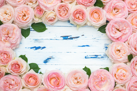 Flowers composition. Frame made of pink rose flowers on aged wooden background. Flat lay, top view, copy space.の写真素材