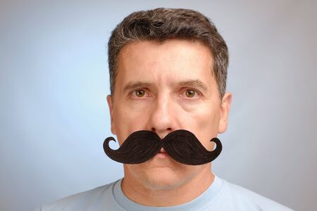 Portrait of a man with a fake mustache to attend an event in November to help men awareness health problems. Close up viewの写真素材