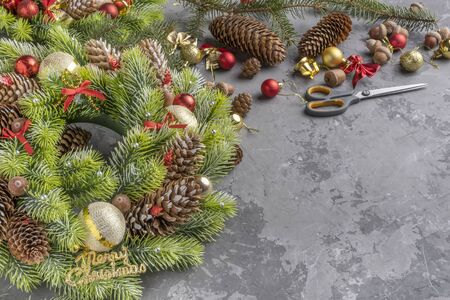top view of Christmas wreath with fir, pine cones, balls , ribbons and acorns on concrete surface with copy space.の写真素材