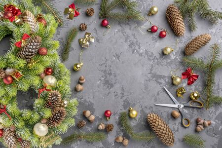 top view of Christmas wreath with fir, pine cones, balls and ribbons on concrete surface with copy space.の写真素材