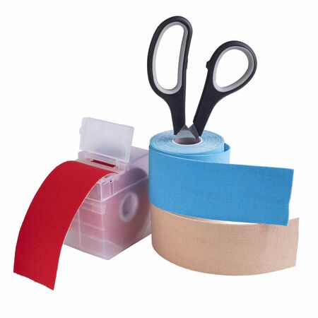 scissors, dispenser and rolls kinesiology tape for athletes isolated on white background. Kinesiology taping manipulate nerve receptors and reduces pain in muscles and speeds up the healing processの写真素材