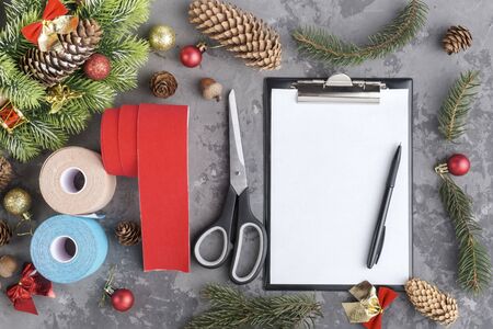 Christmas composition of rolls kinesiology tape for athletes, wreath, fir, pine cones, balls, ribbons and clipboard with pen on grey concrete background, top view, copy spaceの写真素材