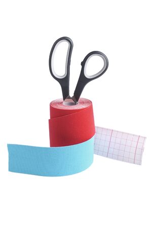two rolls kinesiology tape for athletes and scissors isolated on white background. Kinesiology taping manipulate nerve receptors and reduces pain in muscles and speeds up the healing processの写真素材