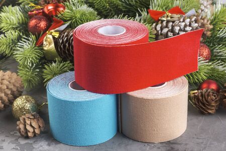 Christmas composition of wreath, fir, pine cones, balls, ribbons and stack rolls kinesiology tape for athletes on grey concrete backgroundの写真素材
