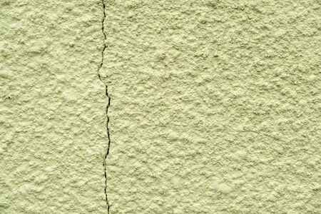 olive painted chipped plaster on the wall weathered with vertical crack.の写真素材