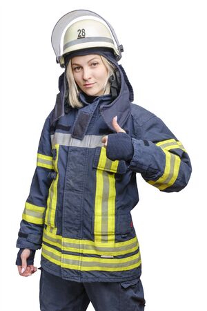 A young smiling fireman girl in a helmet and wearing fireproof uniform, stands and make gesture ok. Isolated on white backgroundの写真素材