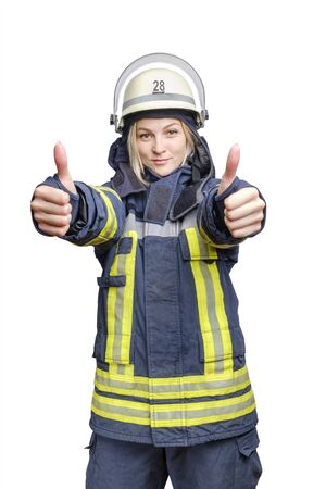 A young smiling fireman girl in a helmet and wearing fireproof uniform, stands and make gesture ok with two hands. Isolated on white backgroundの写真素材