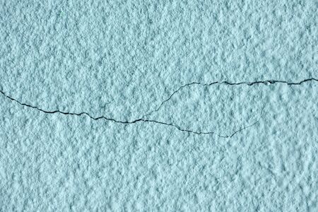 blue painted chipped plaster on the wall weathered with two horizontal cracks.の写真素材