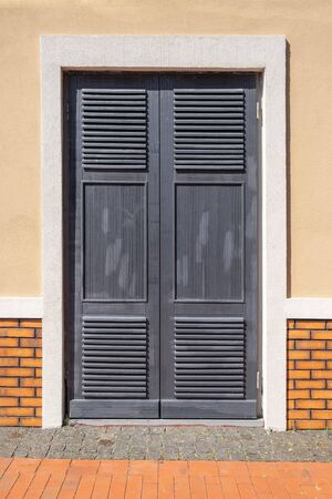 Closed old grey doors on background of yellow wall. front view from streetの写真素材