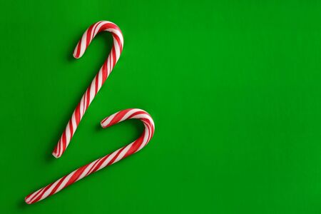 Two christmas red candies on a green paper background. Copy space for text.の写真素材