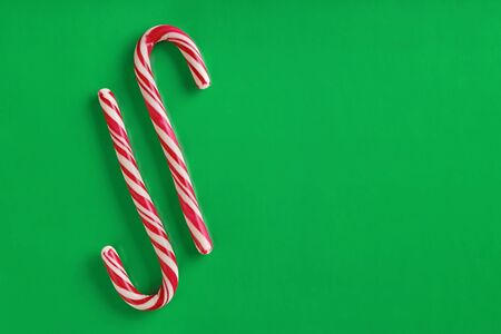 Two christmas red and white candy canes on a textured green paper background. Copy space for text.の写真素材
