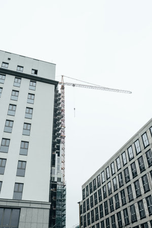 Top of building under construction with building crane. Foggy cloudy sky, copy space