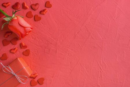 Festive composition from red rose, tied gift box and hearts scattered on pink background, valentines day concept, copy space for text, flatlayの写真素材