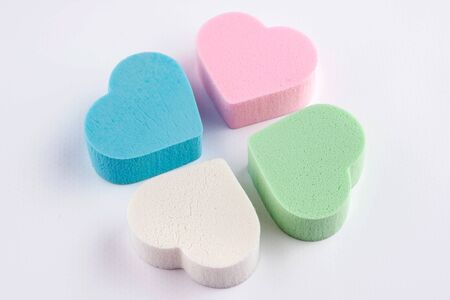 Assorted pink, blue, green and white pastel cosmetic sponges in heart shape on white background. skin care and beauty concept. Close up viewの写真素材