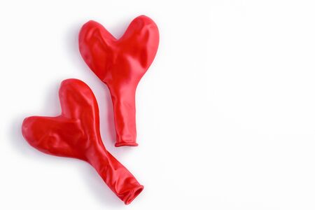 two not inflated heart shaped red balloons on white background, concept love, Valentine's day, greeting cardの写真素材