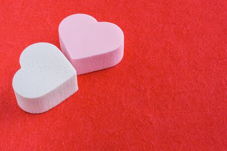 pink and white pastel cosmetic sponges in heart shape on red felt background. skin care and beauty concept. closeup viewの写真素材