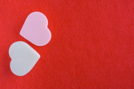 pink and white pastel cosmetic sponges in heart shape on red felt background. skin care and beauty concept. top view, flatlayの写真素材