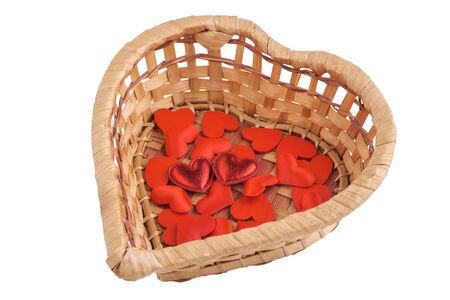 Small hearts in a wicker heart-shaped basket isolated on white. Close-up viewの写真素材