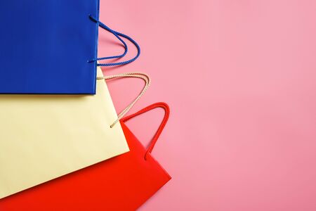 three paper shopping bags on pink background with copy space for brand or advertising text. Top view, flat lay, sale conceptの写真素材