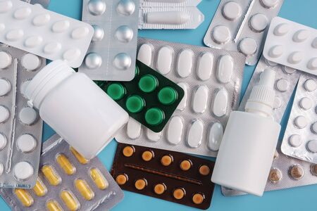 pile of various shapes and sizes of drugs in different packaging on a blue background. top view, flatlayの写真素材