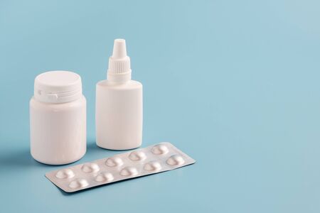 two white plastic medicine bottles for pills without labels and pill packaging on blue background closeup. Copy space for text or advertising. Pharmacy Shopping Concept.の写真素材