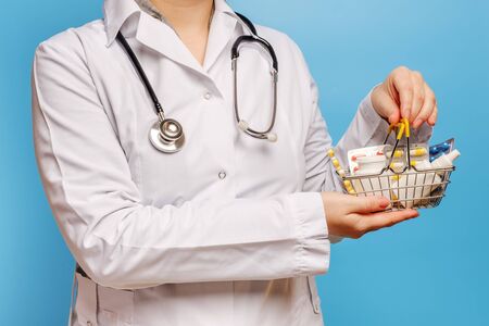 Doctor's hands are holding shopping cart with various pills, tablets and medicine bottles.の写真素材
