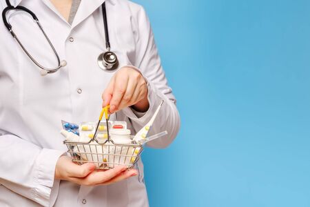 Doctor's hands are holding shopping cart with various pills, tablets and medicine bottles, copy spaceの写真素材